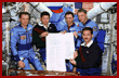  Crewmembers with a scroll they signed commemorating the 50th anniversary of the United Nations 